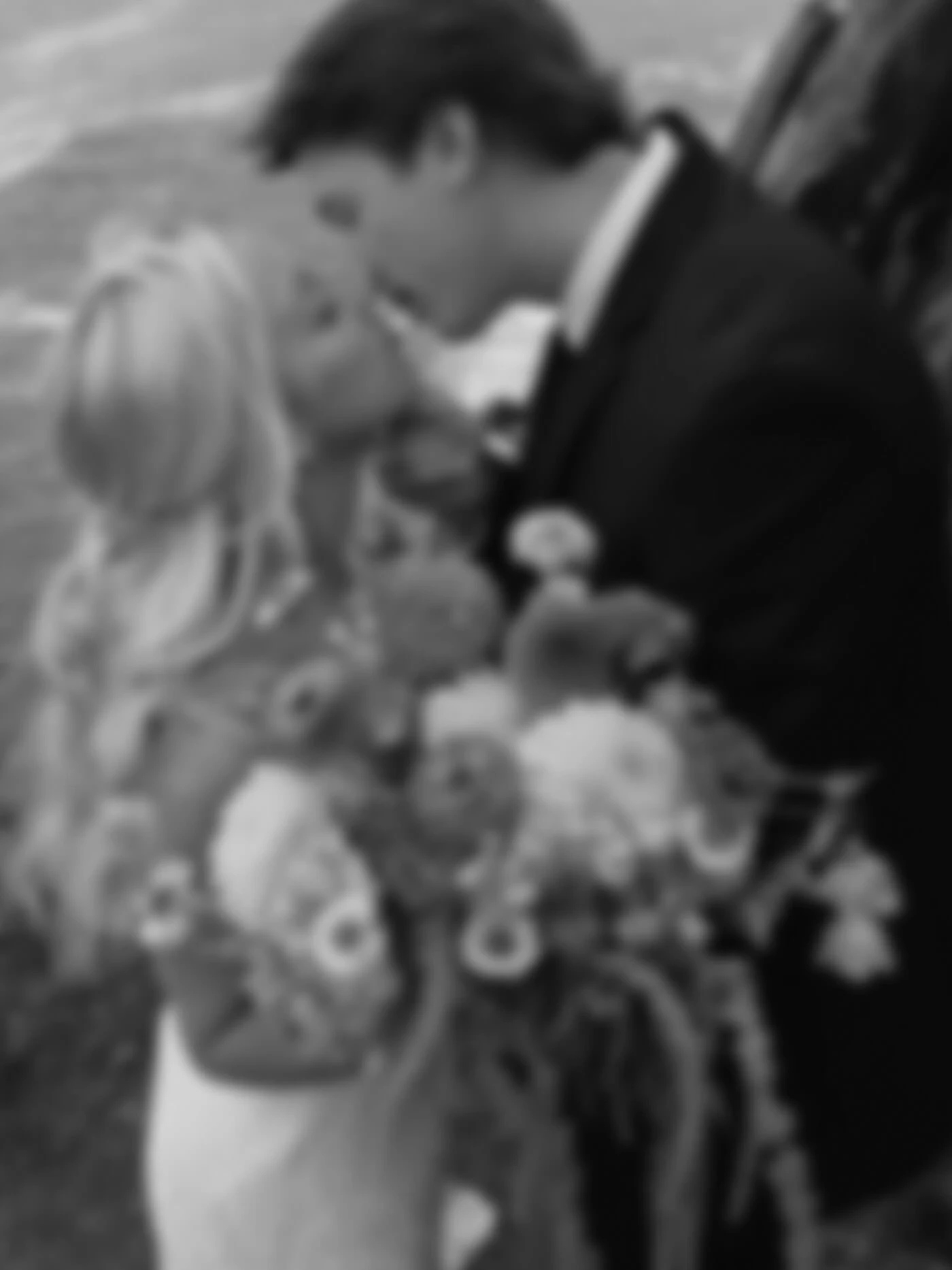 Сouple wearing a white gown and a black suit width flowers balck and white photo
